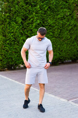 Man in summer outfit outside. A man strolls along a paved path wearing a light gray outfit and...