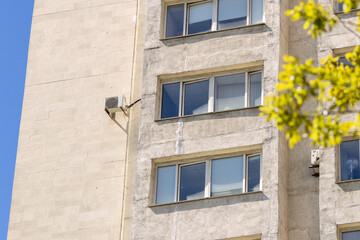 air conditioner on wall of an apartment building with view of green trees. ventilation and cooling of home or office during hot weather. installation maintenance of fan air conditioner. summer heat