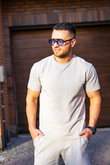 Man wearing sunglasses stands outdoors. A man enjoys the warm sunlight while standing casually with...