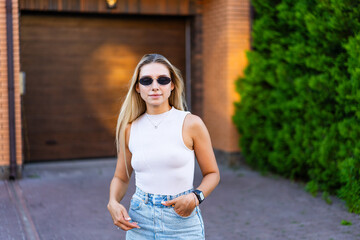 Young woman enjoys sunny day outdoors. A young woman stands confidently outside a modern home,...