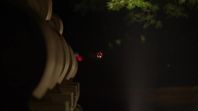 Night scene featuring traditional Chinese roof eaves and a distant red light in darkness