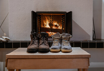 Pair of winter boots drying in front of fireplace indoors cozy home atmosphere