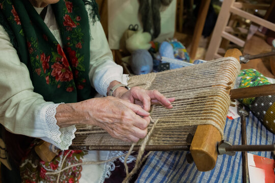 Skilled artisan weaving fabric on traditional loom with colorful threads and intricate patterns