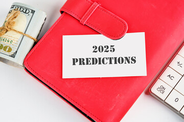 Text 2025 predictions on a business card on a red notebook with dollars and a calculator lying next...