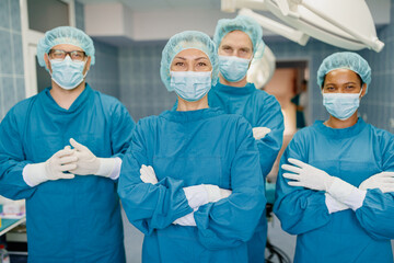 Confident Diverse Team of Surgeons in Operating Room Wearing Surgical Gowns and Masks