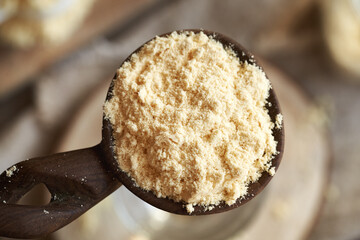 A heap of whey protein powder on a wooden spoon