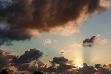 yellow-brown sunset with rain clouds illuminated by sunlight
