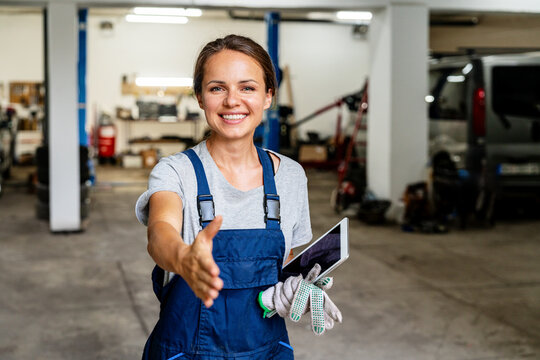 Friendly female auto mechanic greeting client in local auto repair. - Powered by Adobe