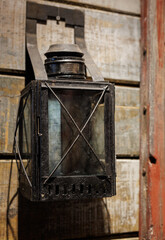 Old rusty metal railway lantern with a glass lens. Historical industrial lighting equipment from the past.