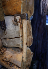 An antique hand axe with a wooden handle is mounted on a wooden wall.