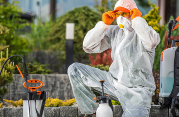 Pest Control Worker Prepares Equipment in Protective Gear at a Garden