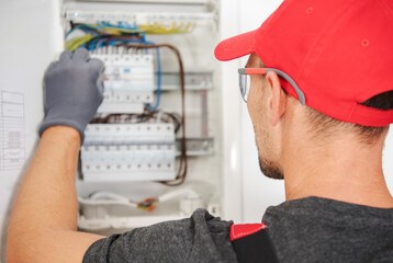 Electrician Working on Circuit Box in Residential Setting During Daylight