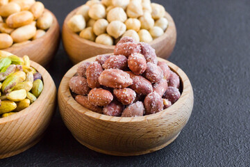 Salted, in-shell peanuts designed in a bamboo bowl on black surface