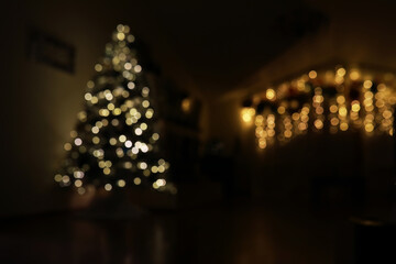 Obraz premium Cozy Christmas Living Room with Blurred Christmas Tree and Illuminated Festive String Lights