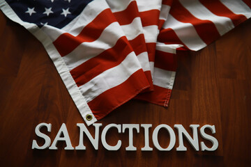American Flag with Sanctions Text on Wooden Background - Political and Economic Concept Image