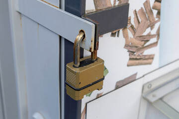 A weathered padlock on a metal bar