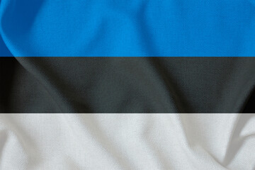 flag of the Republic of Estonia with three horizontal stripes on a rough canvas with folds