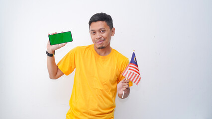 Asian man wearing yellow T-shirt and holding smartphone and Malaysian flag