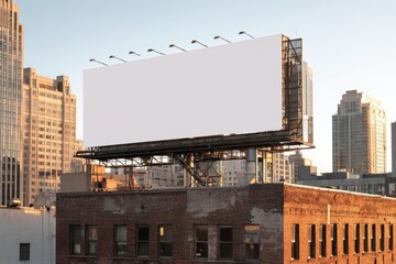 Obraz premium Outdoor advertising mockup on a large empty billboard surrounded by cityscape during sunset with urban buildings in view