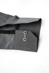 Detailed view of a gray dress shirt sleeve with stitched cuff and two buttons, isolated on a white...