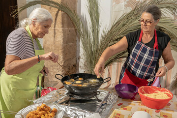 Two Mallorcan women frying fritters. Bunyols, typical food from Mallorca.
