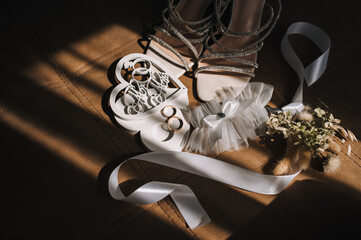 Photo of the bride's wedding accessories in a room with shade from the sun on the floor: shoes, a...