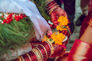 Bride holding flower petals in her hands during traditional hindu wedding ceremony