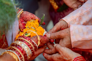 Bride receiving flower petals from grandparents during traditional hindu wedding ceremony