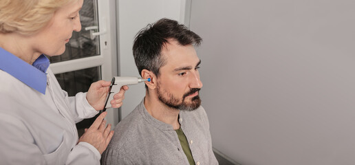 Experienced audiologist with tympanometer probe doing tympanometry procedure and impedance...