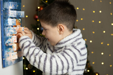 A child takes out a small chocolate from a Christmas advent calendar