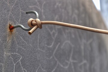 A neatly organized electrical cable secured with a tie and hung on a hook against a simple wall, demonstrating orderly management of wiring or tools.