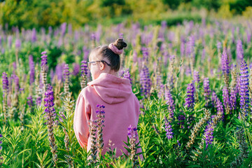 Child with Down syndrome standing in blooming field facing away