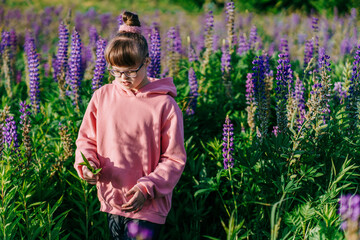 Child with Down syndrome exploring blooming meadow in pink hoodie