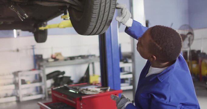 Animation of glowing light over african american man working in car workshop