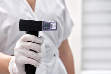 Morpheus body handpiece in beautician hand, on clinic background. Hardware cosmetology