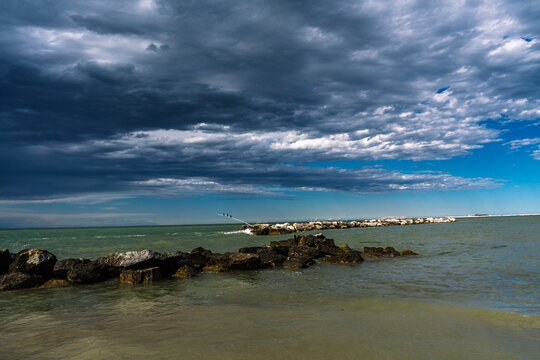 Moody coastal scene with rocky breakwater under dramatic skies. A serene seascape before a storm.