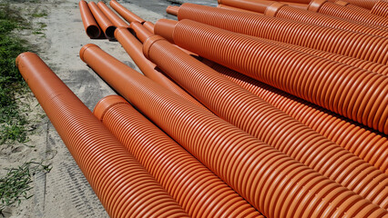 Corrugated sewer pipe, double-layer. Pipes stacked together, repair work in the city. Orange sewer pipes, close-up. Pipes are able to withstand variable loads from the soil