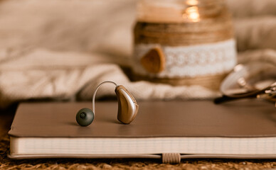 Stylish hearing aid on a soft notebook showcases innovative solutions in audiology and sound...