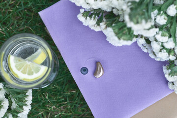 Beige hearing aid on periwinkle by lemonade, flowers. Peaceful daytime nature provides a good mood...
