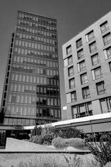 Monochrome low-angle view of two contrasting buildings a tall, modern glass skyscraper and a...