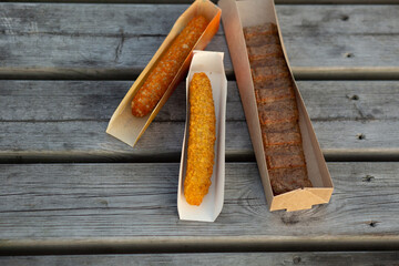 Three different fried snacks in paper trays on rustic wooden table. Perfect food mockup for fast-food branding, street food packaging or menu design.