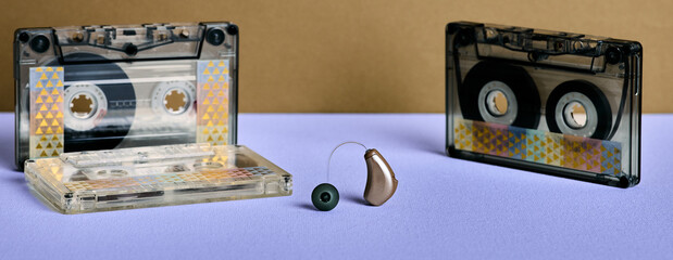 Hearing concept. Hearing aid rests between two cassette tapes, merging audio tech with nostalgic...