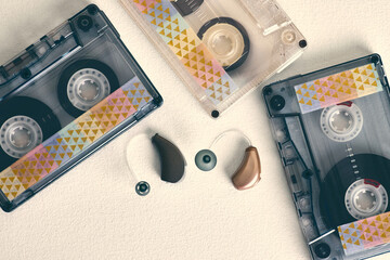 Unique hearing aids alongside vintage audio cassettes illustrate the blend of health technology and...