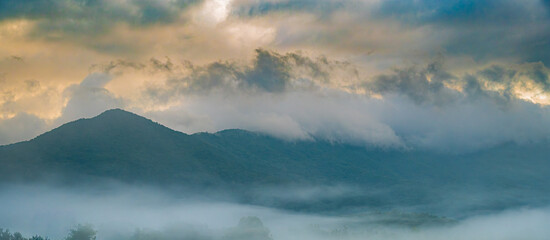 Panorama of a stormy sky at sunrise and rolling fog surrounding mountain peak in the Great Smoky Mountains