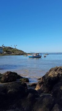 barco no mar com ondas fracas em dia de c&eacute;u azul. registro feito em guarapari, esp&iacute;rto santo 