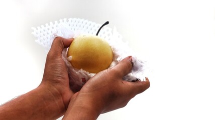 A fresh green pear, cut in half, with one half wrapped in clear plastic film, presented on a clean...