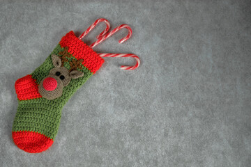 Knitted green Christmas stocking with red elastic band, heel, and toe. Decorated with a Rudolph the...