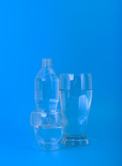 Glasses and plastic water bottle on blue background