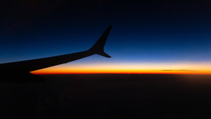 Airplane's wing  in the sky at sunset silhouette