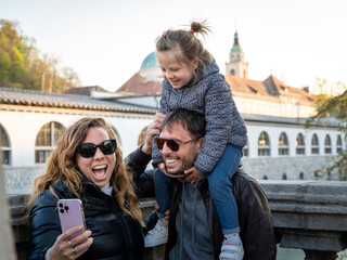 Familia conformada por padre, madre e hija pasando un lindo momento juntos y tomándose una selfie